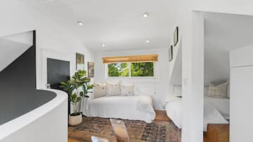 A bedroom with a bed, a potted plant, a window with a view, and a staircase.