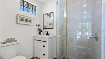 A modern bathroom with a toilet, vanity, and a glass shower enclosure.