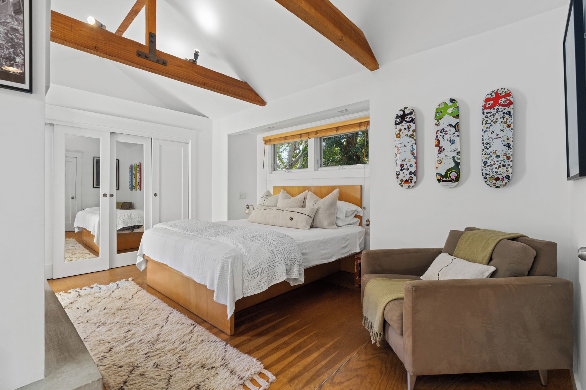 A bedroom with a wooden bed, a brown sofa, and a large window.