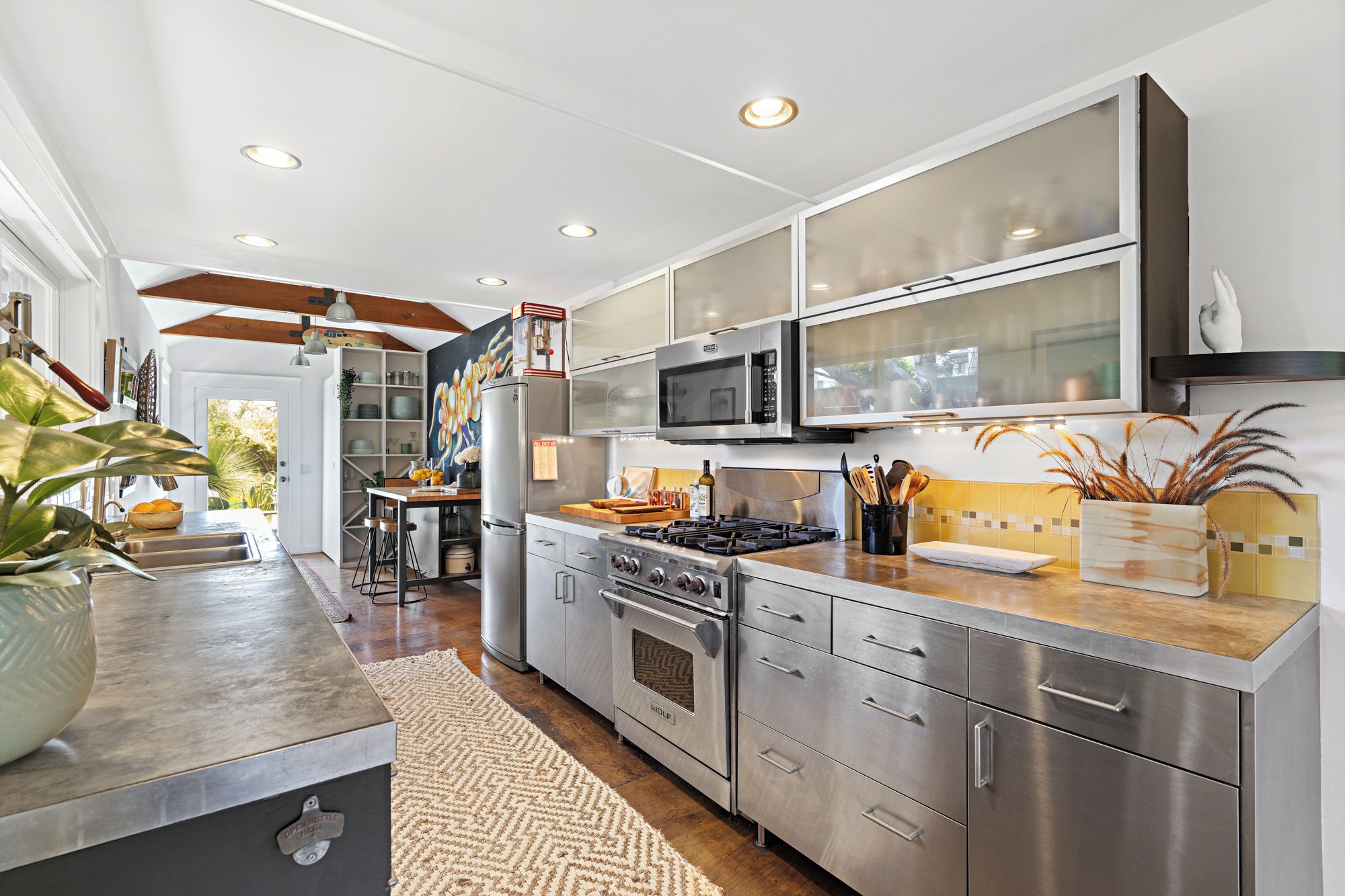 A modern kitchen with stainless steel appliances, a wooden island, and a view to the outdoors.