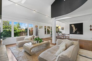 Un salón espacioso con un ventanal grande, un comedor y una obra de arte moderna en la pared.