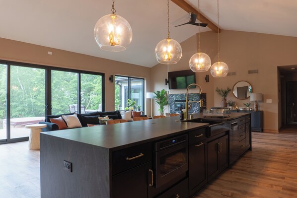 Una cocina moderna con una isla central, electrodomésticos integrados e iluminación colgante.