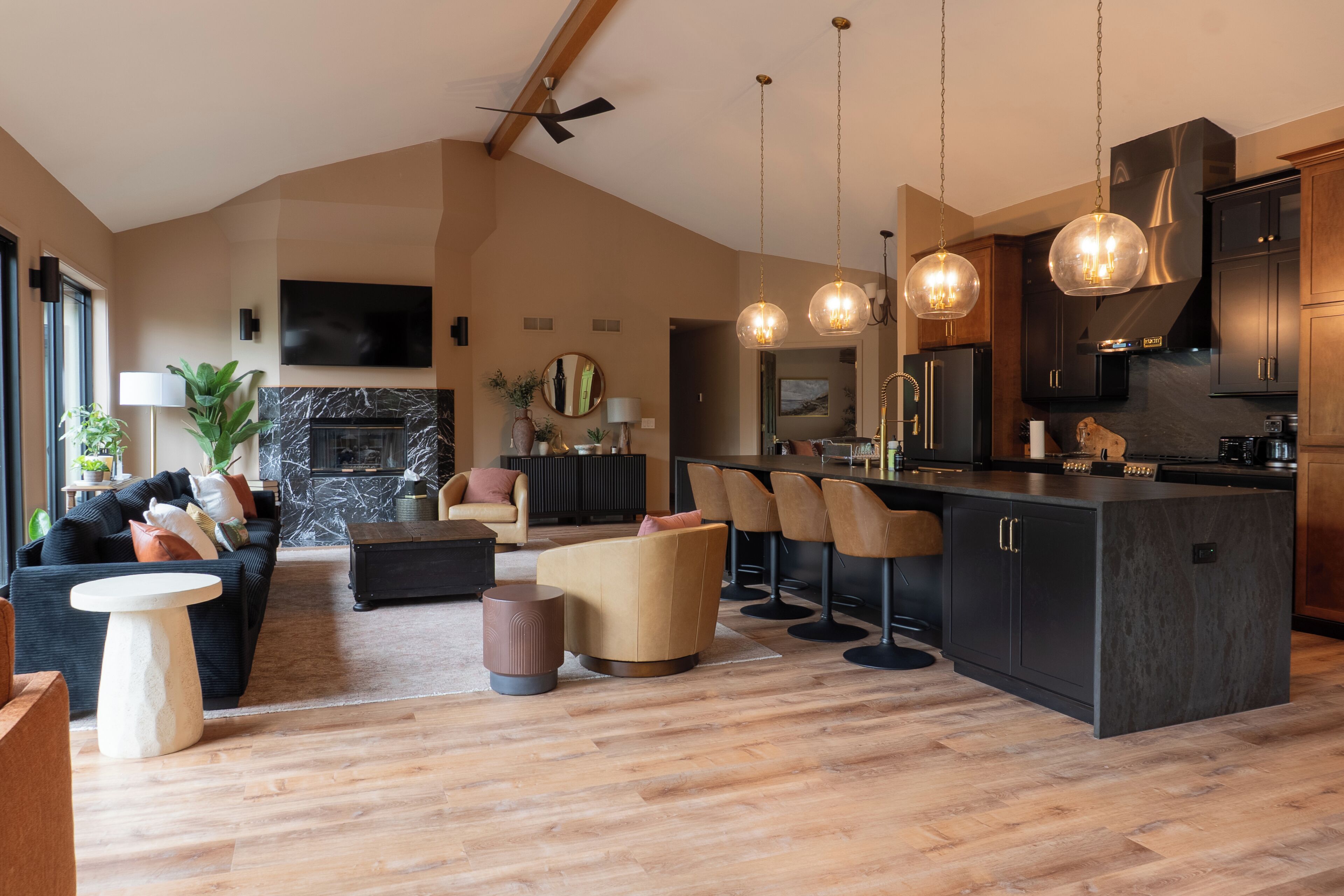 A modern kitchen with dark cabinetry, a central island, and bar stools.