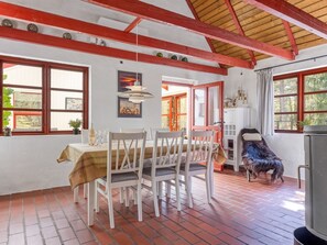 A dining area with a brick floor, white chairs, a table with a cloth, and a red-framed window. - "Jooseppi" - 4.8km from the sea by Interhome (Læsø)