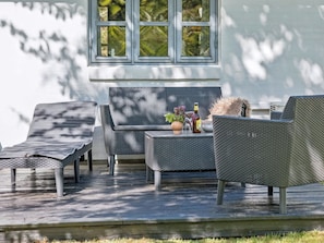 A patio with wicker furniture, a sofa, and a table with a bottle and flowers. - "Thorvor" - 900m from the sea by Interhome (Asnæs)