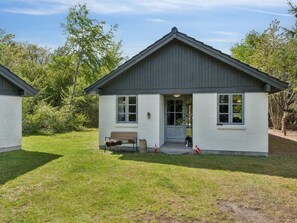 A small, single-story building with a gabled roof, a front door, and a bench outside. - "Thorvor" - 900m from the sea by Interhome (Asnæs)