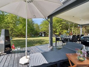 Un patio exterior con una parrilla, asientos y vistas al jardín trasero.