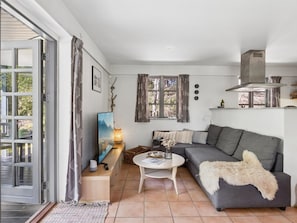 A modern living room with a grey sofa, a round white coffee table, a TV on a wooden stand, and a large window with curtains. - "Thorvor" - 900m from the sea by Interhome (Asnæs)
