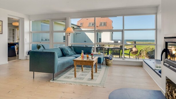 Un salon spacieux avec une grande fenêtre, un canapé bleu, une table basse en bois et une cheminée.