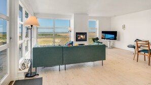 Un salon moderne avec un canapé vert, un téléviseur et un coin repas comprenant une chaise.