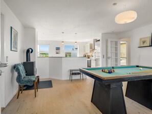 Une pièce moderne équipée d’une table de billard, d’un fauteuil confortable et d’une cheminée.