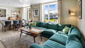 Una sala de estar con un sofá verde, una mesa de centro de madera y un comedor con una mesa y sillas.