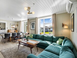 Ein Wohnzimmer mit einem grünen Sofa, einem Holztisch und einem Essbereich inklusive Tisch und Stühlen.
