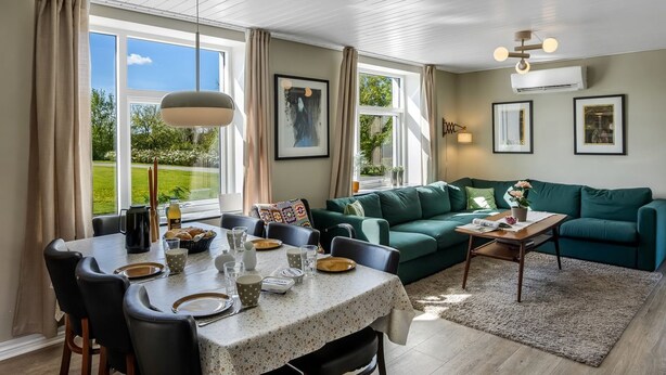 Una sala de estar moderna con comedor, ventanas amplias y un sofá verde.