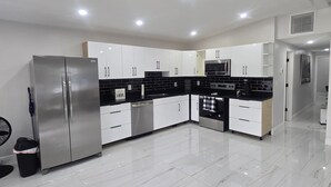 A modern kitchen with white cabinets, stainless steel appliances, and a glossy marble floor.