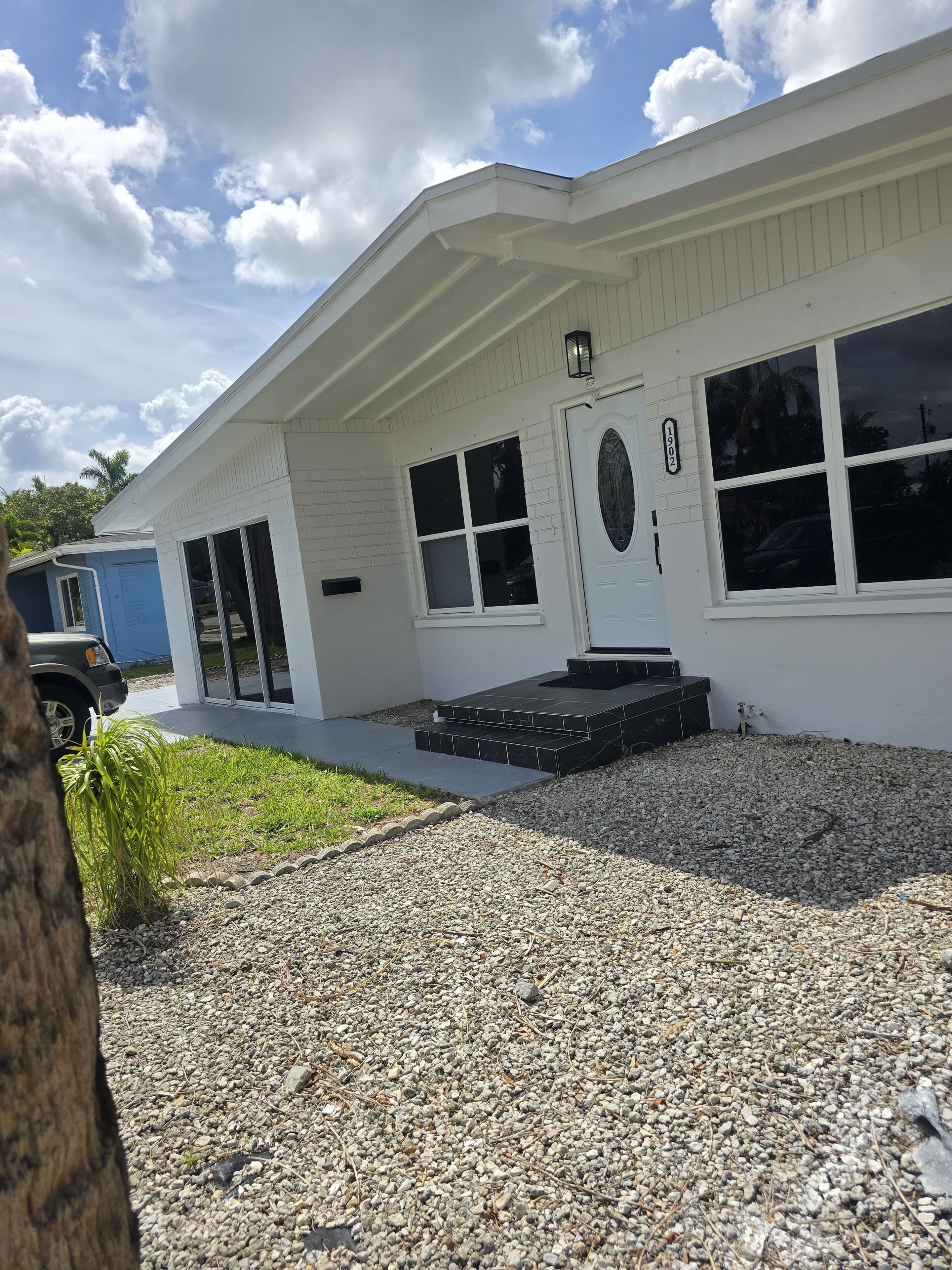 A white building with a front door, two windows, and a small porch.