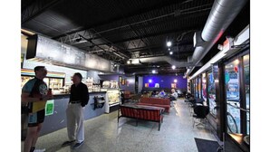 Un espacio interior con mostrador, zona de asientos y vistas a través de un muro de cristal.