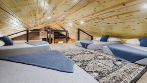 Ein gemütliches Schlafzimmer im Dachgeschoss mit Holzsperren, einem integrierten Kamin und einer kleinen Treppe.
