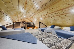 Ein gemütliches Schlafzimmer im Dachgeschoss mit Holzsperren, einem integrierten Kamin und einer kleinen Treppe.