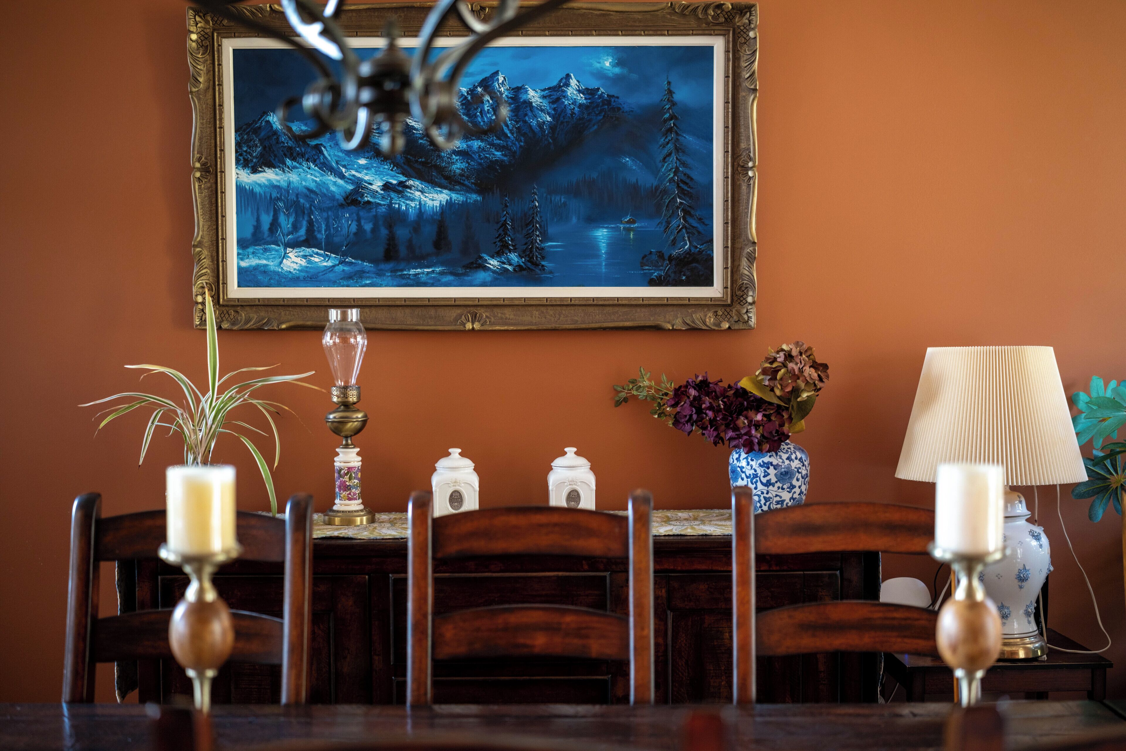 A dining table with chairs, a framed painting, and decorative items.