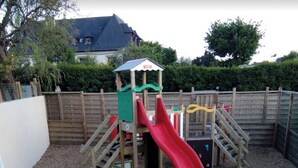 Un parque infantil con un tobogán rojo y estructuras para escalar.