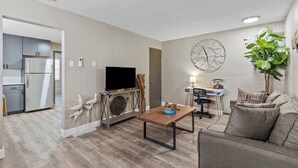 Ein modernes Wohnzimmer mit einem Flachbildfernseher, einem Holztisch, einer Couch und einem Essbereich mit einer Lampe.
