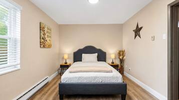 A bedroom with a bed, bedside tables, a star decoration, and a window with blinds.