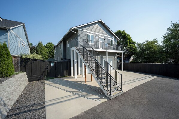 A two-story house with a front porch and a staircase leading to the upper level. - Cozy Apartment Near Marina | Boating & Hiking | Perfect Getaway (Coeur d'Alene)
