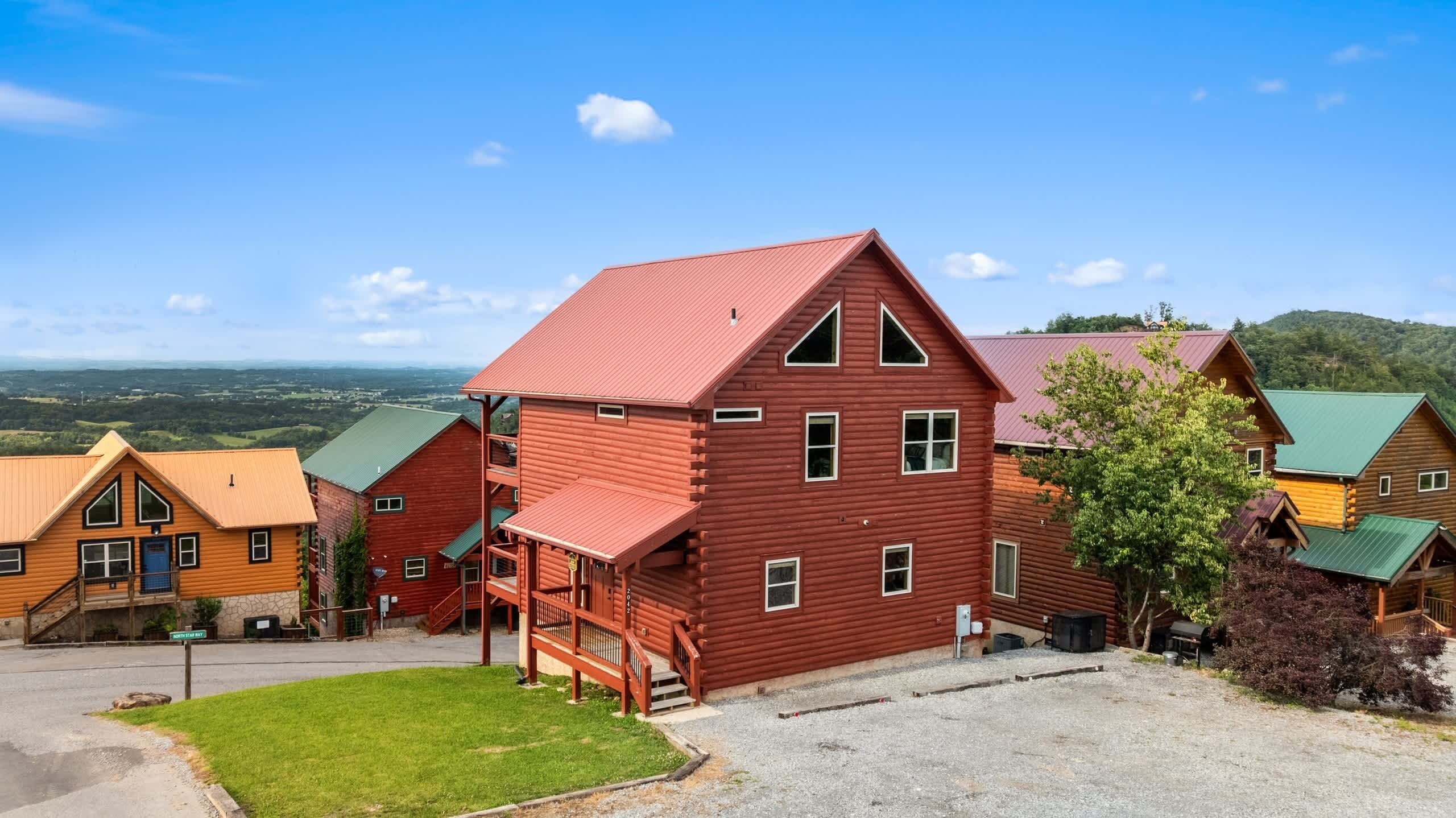 Une cabane en bois rouge avec un balcon, une pelouse verte et une vue sur une vallée.
