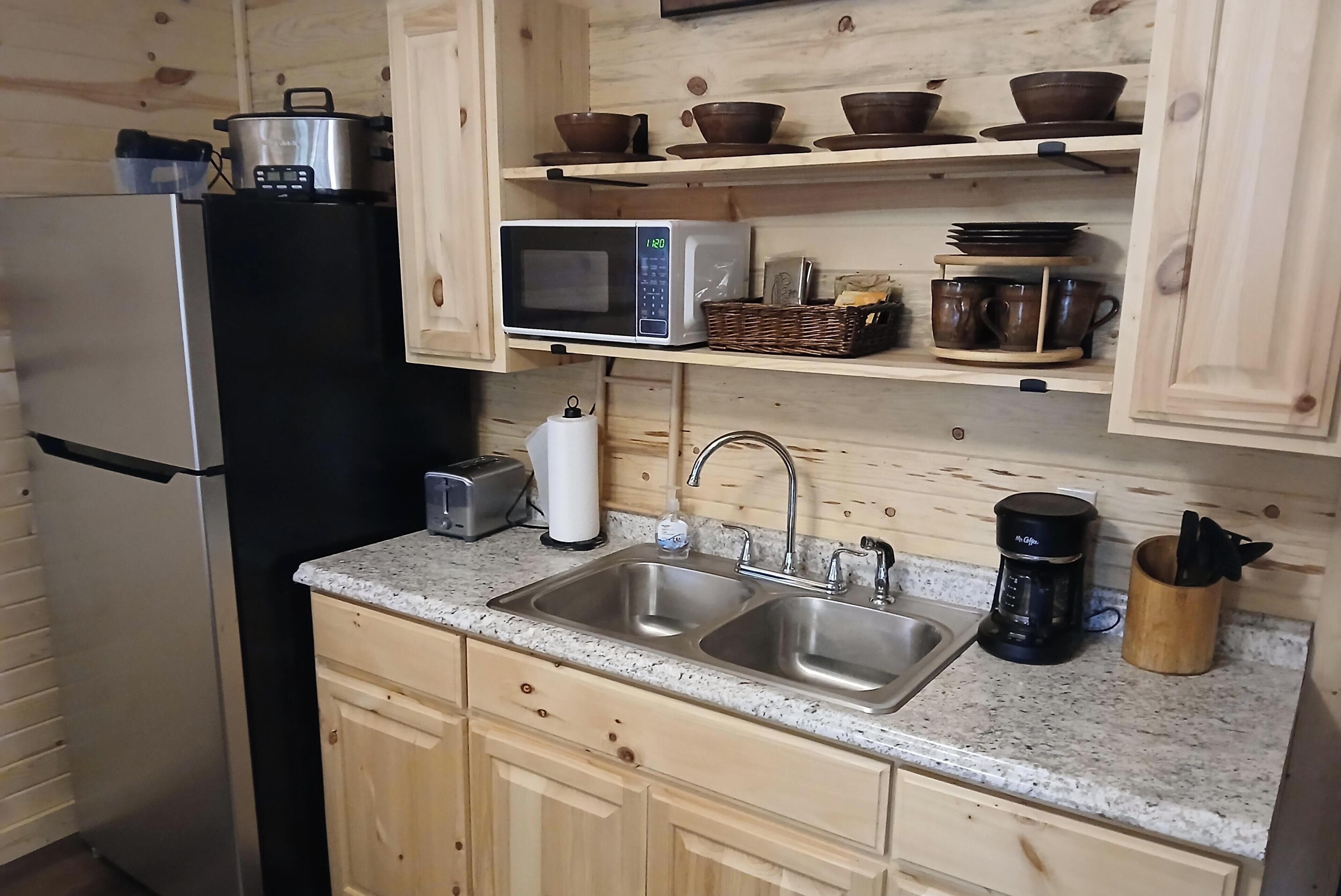 Une cuisine  équipée d’un réfrigérateur en acier inoxydable, d’un four à micro-ondes, d’un évier et de meubles de rangement en bois.