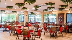Een restaurant met binnenzitplaatsen, grote ramen en hangplanten.