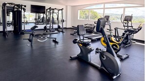Un gimnasio con máquinas de cardio, equipo de levantamiento de pesas y mancuernas.