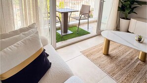 Un balcon avec une table et des chaises, un canapé avec des coussins et une plante en pot.