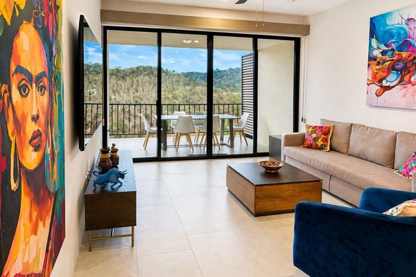Colorful living with Friday artwork and view of the Sierra Madre mountains. Living room has both sheer and blackout manual shades.