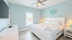 A bedroom with a bed, a ceiling fan, a window with blinds, and a wall decoration. - Luxury private House + Pool. Walk to the beach (North Myrtle Beach)