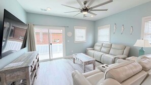 A living room with a ceiling fan, a TV, a sofa, a coffee table, and a view of the outside. - Luxury private House + Pool. Walk to the beach (North Myrtle Beach)