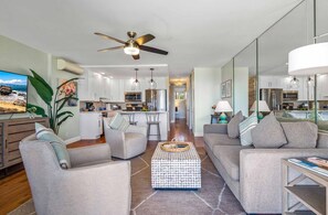 A modern living room with a sofa, armchairs, a coffee table, and a TV. - Remodeled One BD Ocean, AC,wifi, pool, Luana Kai D202 (Kihei)