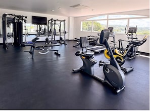 A gym with cardio machines, weightlifting equipment, and dumbbells.