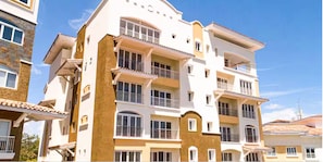 A multi-story residential building with balconies, large windows, and a flat roof.
