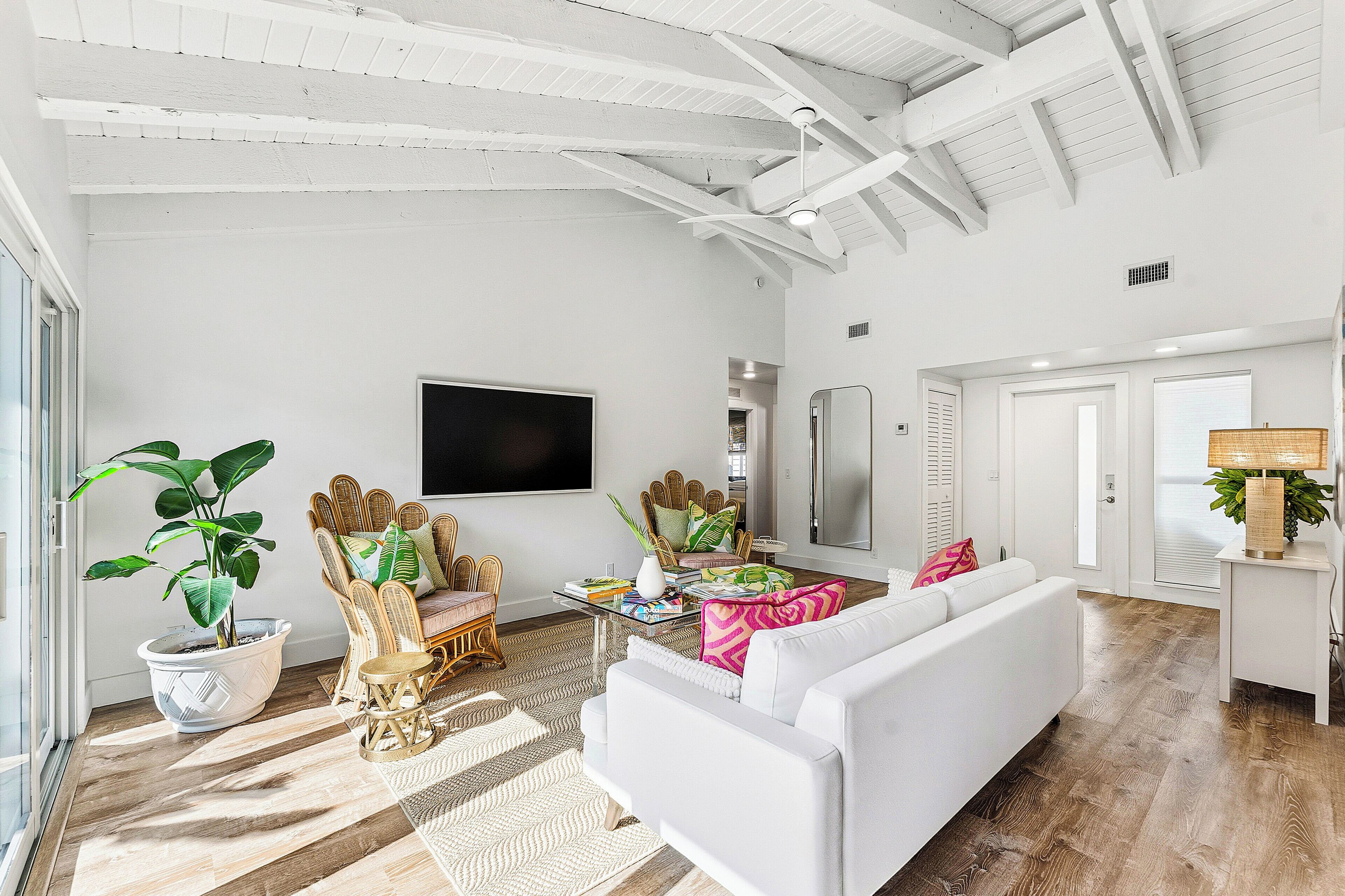 A spacious living room with a white sofa, a television, and a large window.