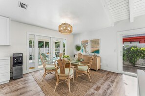 A modern kitchen with a glass dining table, wicker chairs, and a built-in water dispenser.