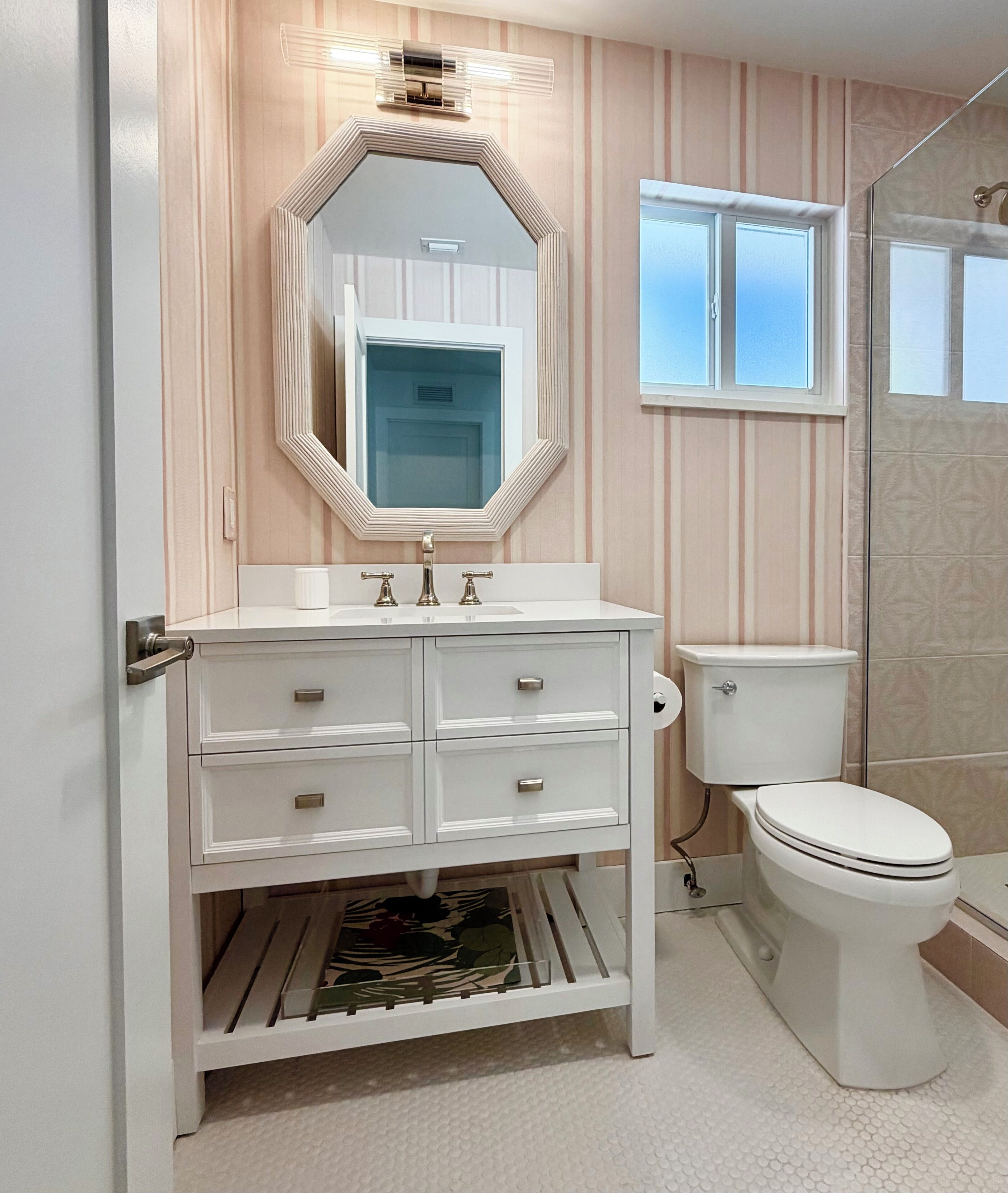 Un baño con tocador blanco, un espejo grande, inodoro y zona de ducha.