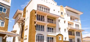 A multi-story residential building with balconies, large windows, and a clear sky.