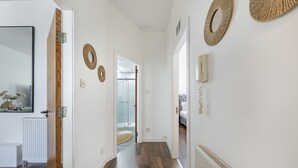 A hallway with wooden flooring, white walls, and decorative woven wall hangings. - Bon Accord Suite - Grampian Lettings (Aberdeen)