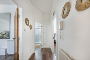 Ein Korridor mit Holzboden, weißen Wänden und dekorativen Wandteppichen.