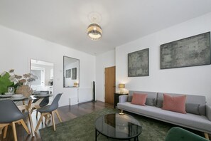 Un salon moderne comprenant un coin repas, un canapé, une table basse et un grand miroir.