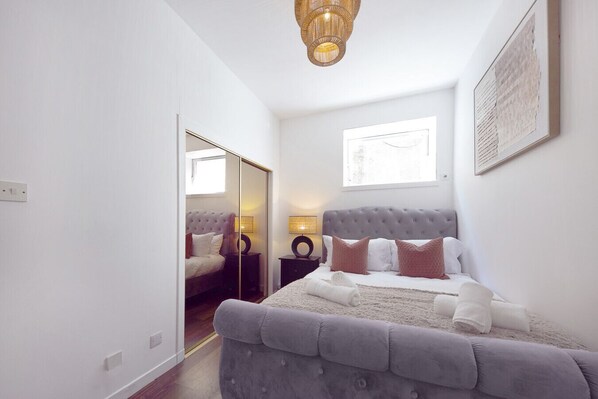 A bedroom with a large bed, a wardrobe, a bedside table, a lamp, and a window. - Bon Accord Suite - Grampian Lettings (Aberdeen)
