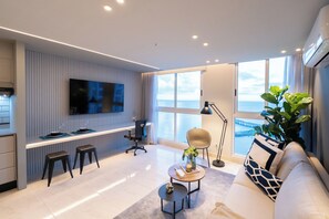 Ein modernes Wohnzimmer mit großem Fernseher, einer Couch, einem Couchtisch und Meerblick.