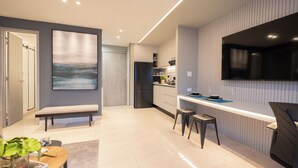 A modern kitchen with a built-in TV, a bench, and a dining area with a table and chairs. - Modern 1BR Ocean View | The Sands Pool High Floor (Panamá)