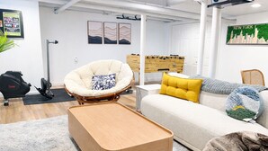 En moderne stue med sofa, stol, sofabord i træ og træningsudstyr.